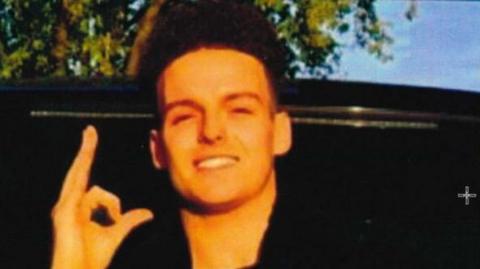 A man smiling at the camera. He is wearing all black 