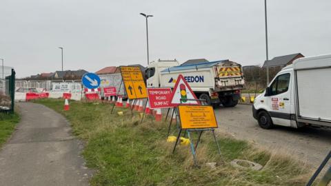 A road with lots of traffic signs and lorries.