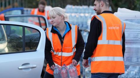 A worker hands out bottled water at the Tunbridge Wells Sports Centre after people in the area experienced a loss of water or low pressure since Saturday evening.