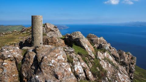 A view point at Dùn Caan, the highest hill on Raasay. The summit is rocky and provides a view over the sea. It is a beautiful sunny day.