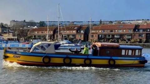 A yellow and blue ferry driving along the Bristol harbour