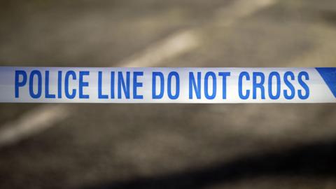 Blue and white police tape which reads 'police line do not cross'