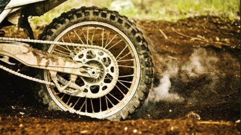 A motorbike kicking up dirt in a field  