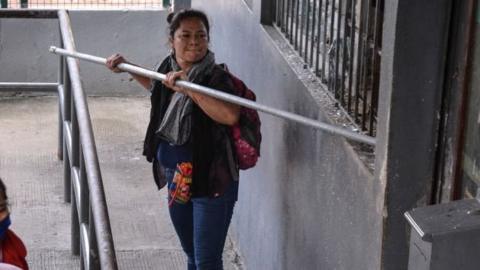 A woman jams a metal pole against a wall