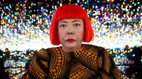 Japanese artist Yayoi Kusama poses for a photograph inside her Infinity Mirrored Room installation titled "The Souls of Millions of Light Years Away" during a media preview of her new exhibition at the David Zwirner gallery in New York, U.S.