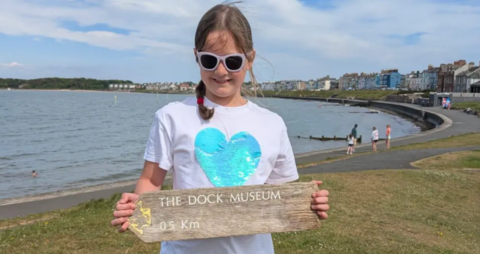 Girl holding up missing museum sign.