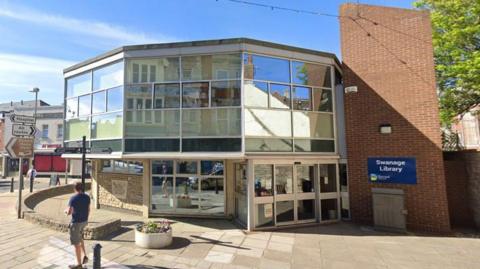 A two-storey, 12-sided, 1960s building with an overhanging upper floor which is mostly glass