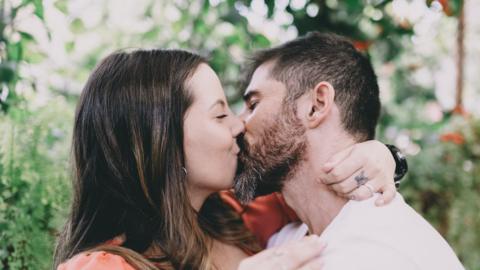 A woman and a man share a kiss.