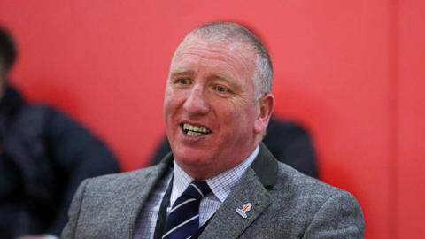 Ralph Rimmer, smiling, dressed in jacket and tie