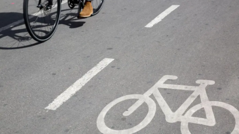 A cyclist pedalling alongside a cycle lane. 