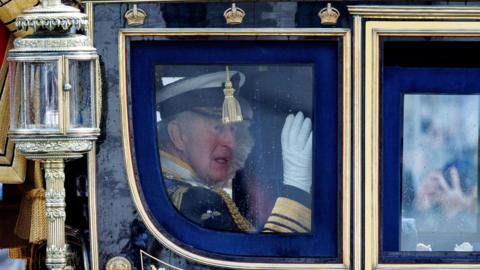 King waves from inside carriage as he heads to Parliament