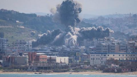 An explosion in Abbasiyeh, a neighbourhood in Tyre, Lebanon. Houses by the seaside as plumes of smoke rise