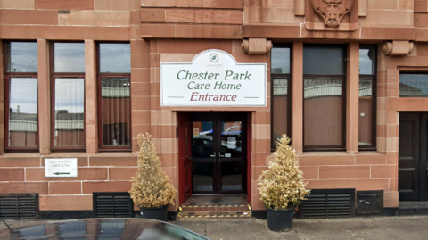 An entrance sign marked Chester Park Care Home above the front door of a red sandstone building