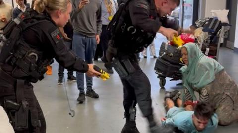 A CCTV still of Mohammed Fahir Amaaz, 20, on the floor during the alleged assault of three police officers at Manchester Airport which has been shown to jurors at Liverpool Crown Court.