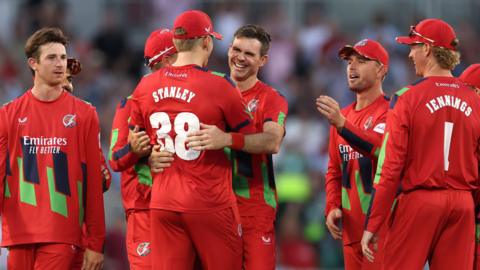 Jimmy Anderson (centre) is hugged by Mitch Stanley (STANLEY 38) with other Lancashire fielders around them after getting the wicket of Joe Root