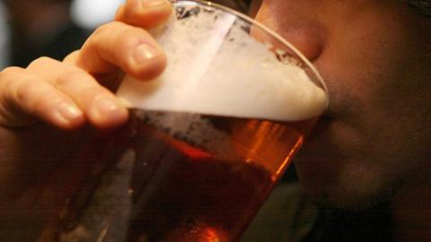 A close up picture of a man drinking a pint of beer