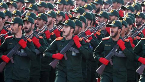 A picture of soldiers in a dark green uniform and red gloves. 