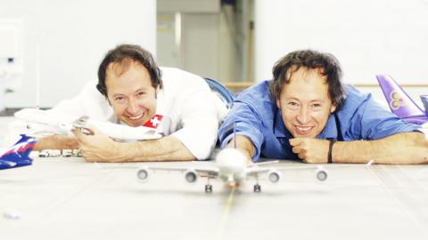 Frederik and Gerrit Braun lying on the floor smiling next to some model planes.