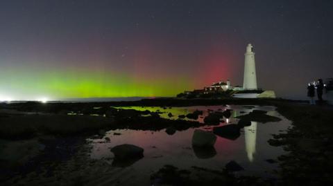 A lighthouse in Whitley Bay in north-east England with green and red aurora
