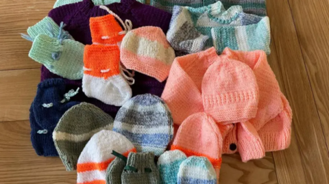 A picture of a number of knitted items. There are different colours, shapes and patterns.