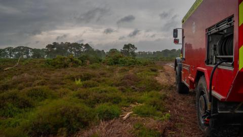 Red fire service Land Rover parked on an area of heathland