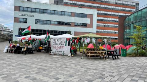 Gazebos outside the Hicks building next to the students' union sporting the Palestinian flag and a banner that reads "Sheffield Campus Coalition for Palestine".