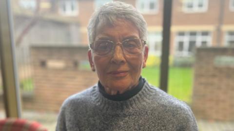 Head and shoulders of Ann Stenfalt wearing a blue jumper and glasses.