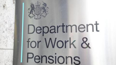 A silver sign that reads "The Department for Work and Pensions"