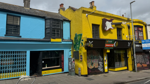 A yellow building is in the process of being painted blue 