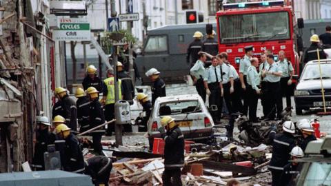 Police officers and firefighters inspecting the damage caused by a bomb explosion in Market Street, Omagh.