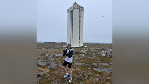Jack Pitcher stood in front of an obelisk in northern Ireland, ready to start his challenge. The weather is grey behind him.
