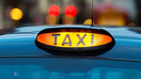 A close-up photo of a black and yellow taxi sign