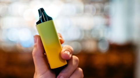 A hand holding a chunky yellow vape