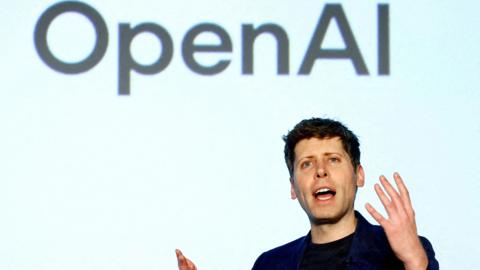 OpenAI CEO Sam Altman speaking on a stage gesturing with his hands.