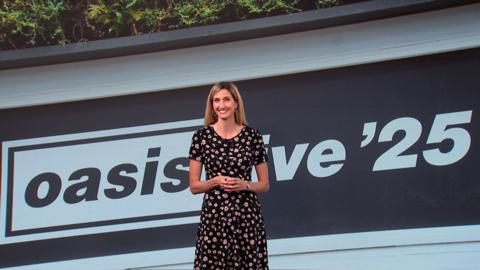 Joy Dunlop stands in front of a black and white backdrop of Oasis live '25