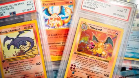 pokemon card collection. They are red-ish cards in plastic casing stacked upon each other.