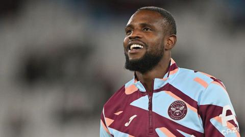 Frank Onyeka warming up for Brentford in his club tracksuit top