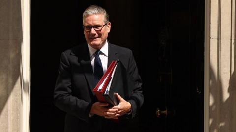 Prime Minister Keir Starmer departs 10 Downing Street to attend his final Prime Minister's Questions at the Parliament in London. He is carrying some files.