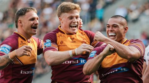 Two Huddersfield players celebrate Tui Lolohea (right) scoring a try 