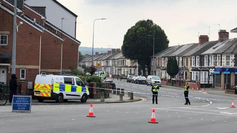 Road closure with one police van, red cones and two police officers on the street