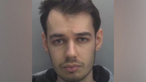 Mugshot of Tyler Webb with short hair looking directly at the camera against a grey background.