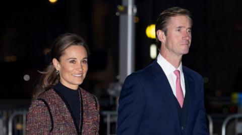 A general view picture of Pippa and James Matthews walking. They are wearing coats.