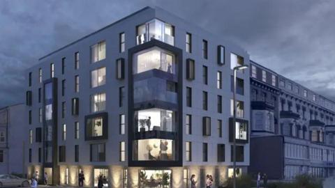 An artist’s impression of The New Ambassador development planned for the former Ambassador Hotel site on Blackpool Promenade. The building is on a corner, in a modern style with large glass windows. 