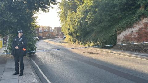 An officer stands at the police cordon on Burrell Road in Ipswich