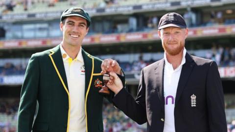 Pat Cummins and Ben Stokes holding the Ashes urn.