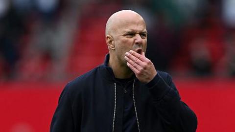 Arne Slot strokes his chin during the defeat to Manchester United