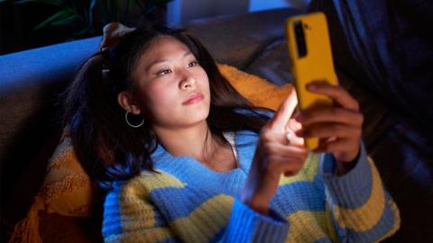 A woman laying down and texting on her phone