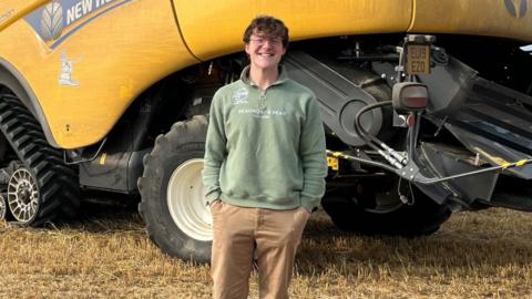 Mike Wilkins smiles in front of a combine harvester