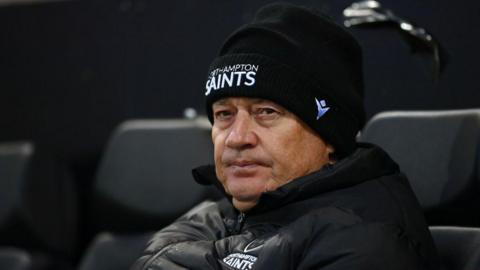 Chris Boyd looks on from the bench while wearing a Northampton Saints beanie
