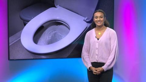 Nina in the studio with a toilet in the screen